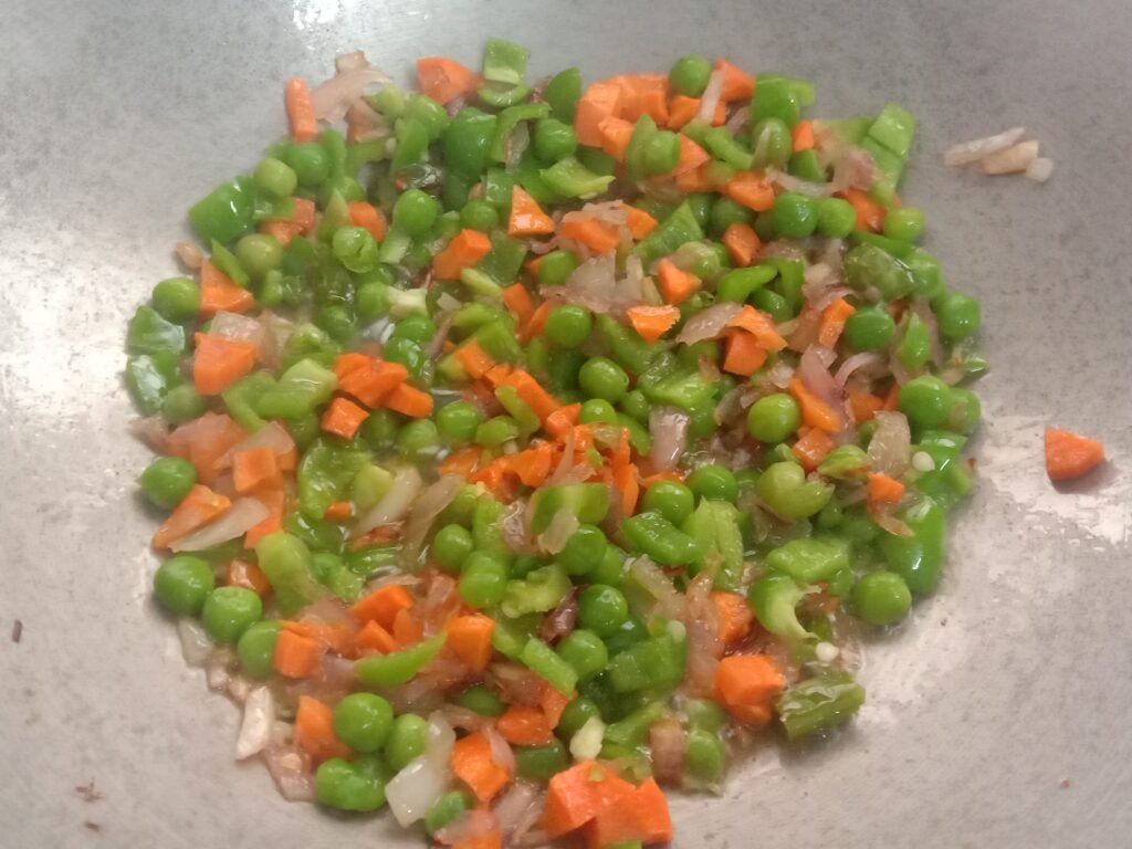 Frying chopped Carrots, green peas and capsicum in pot, Egg bhurji maggi noodles recipe.