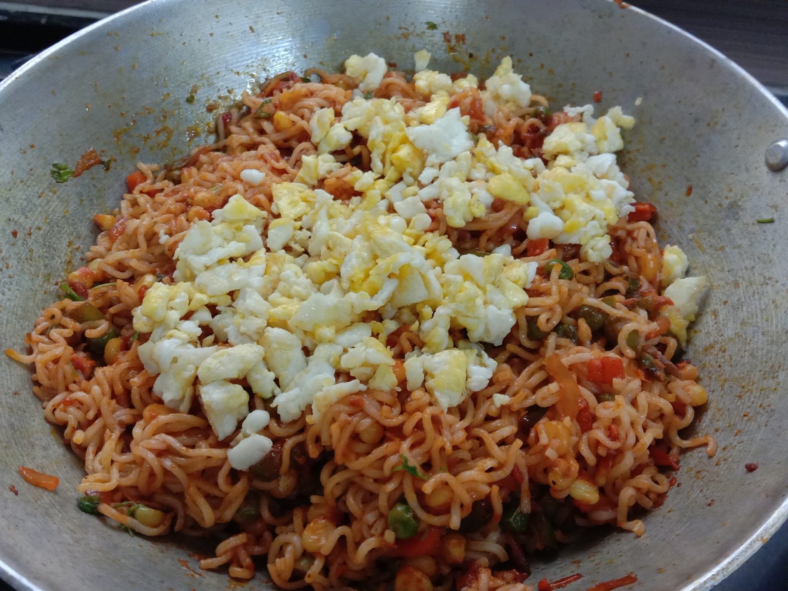 Adding scrambled eggs in to ingredients in pot, Egg bhurji maggi noodles recipe.