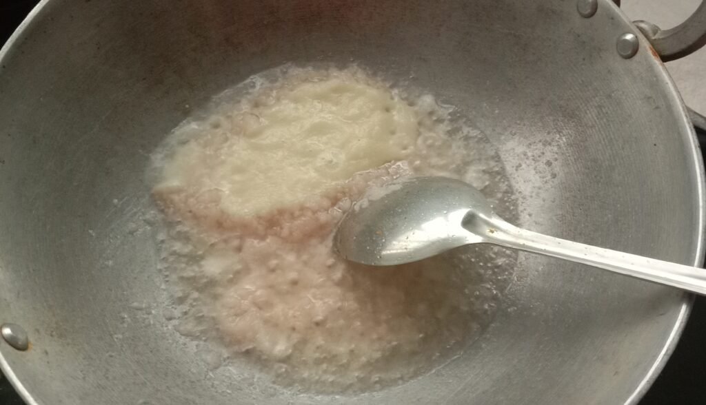 Adding ginger garlic paste in kadhai, Kolhapuri chicken curry recipe.