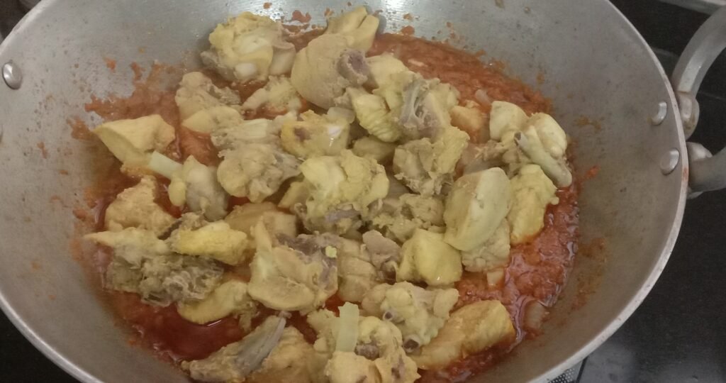 Adding chicken pieces to kadhai, Kolhapuri chicken sukka-curry recipe.