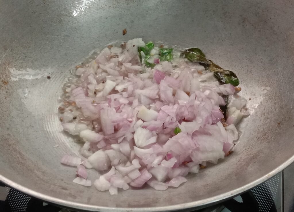Adding chopped onions in tadka, Poha recipe.