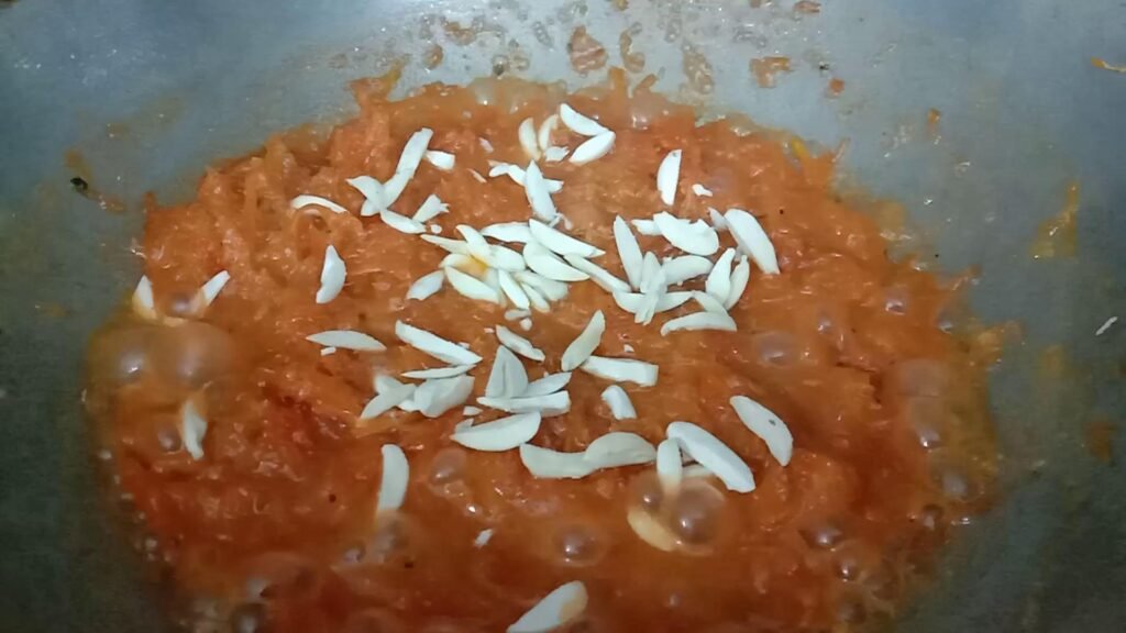 Adding chooped almonds to halwa, Gajar ka halwa recipe.