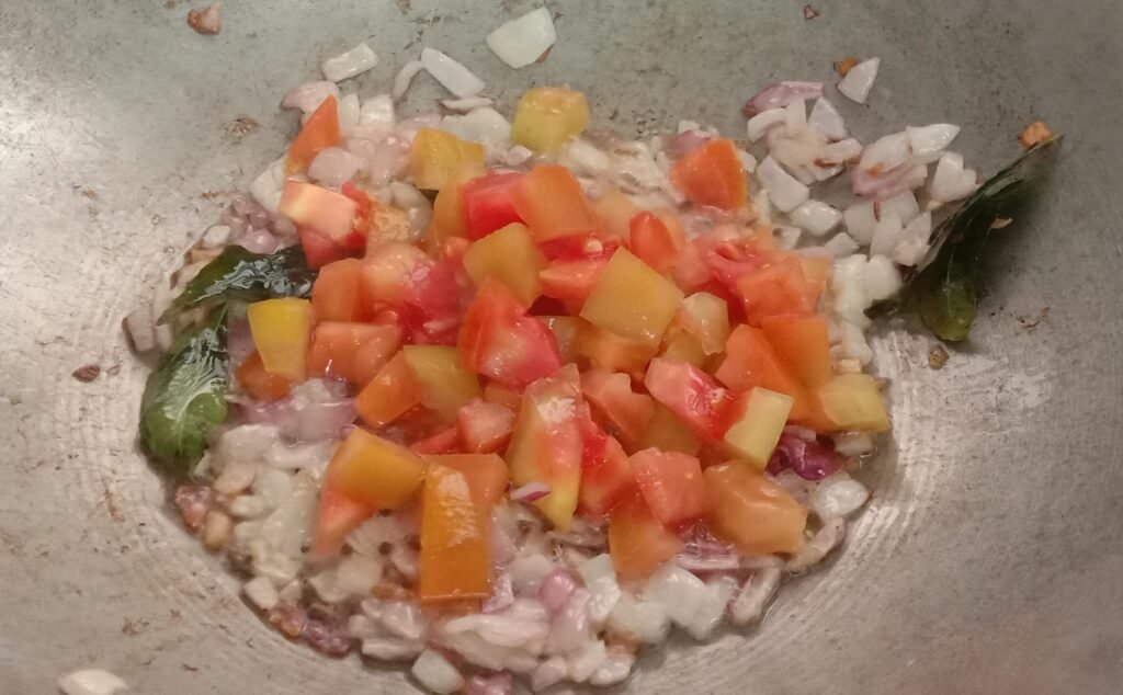 Adding chopped tomato to kadhai, Okra recipe.