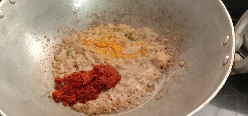 Adding red chilli powder and turmeric powder to kadhai, hindi masala recipe.