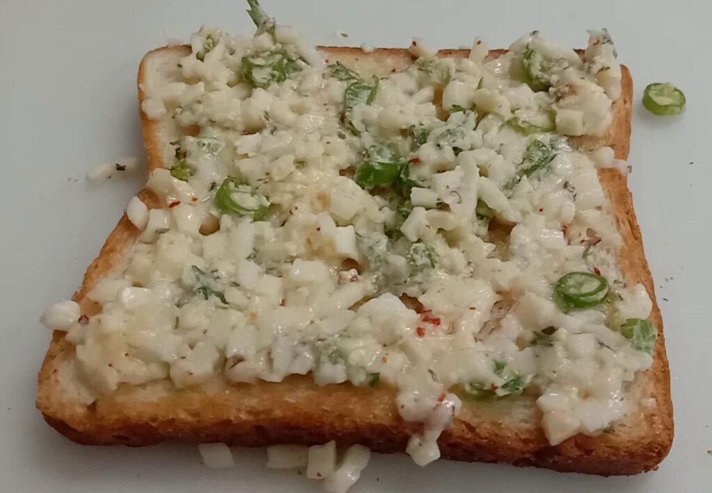 Spreading cheese mix on bread, Chilli cheese toast. 