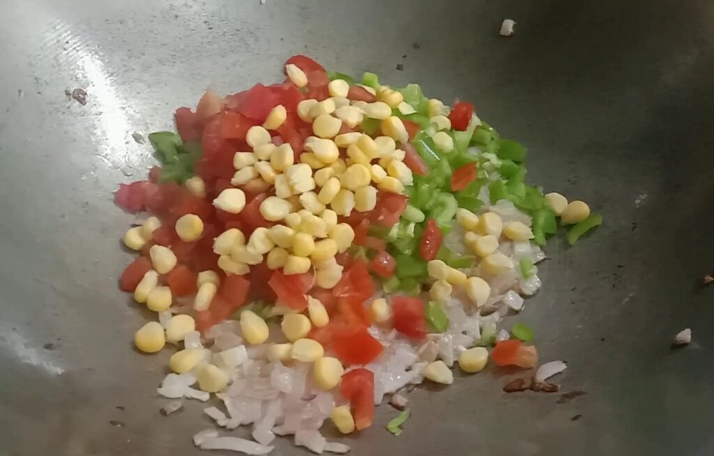 Adding Chopped tomatoes, Capsicum and corn seeds.