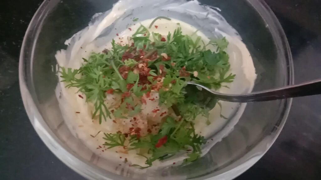 Whisked butter, garlic paste and coriander leaves in mixing bowl.