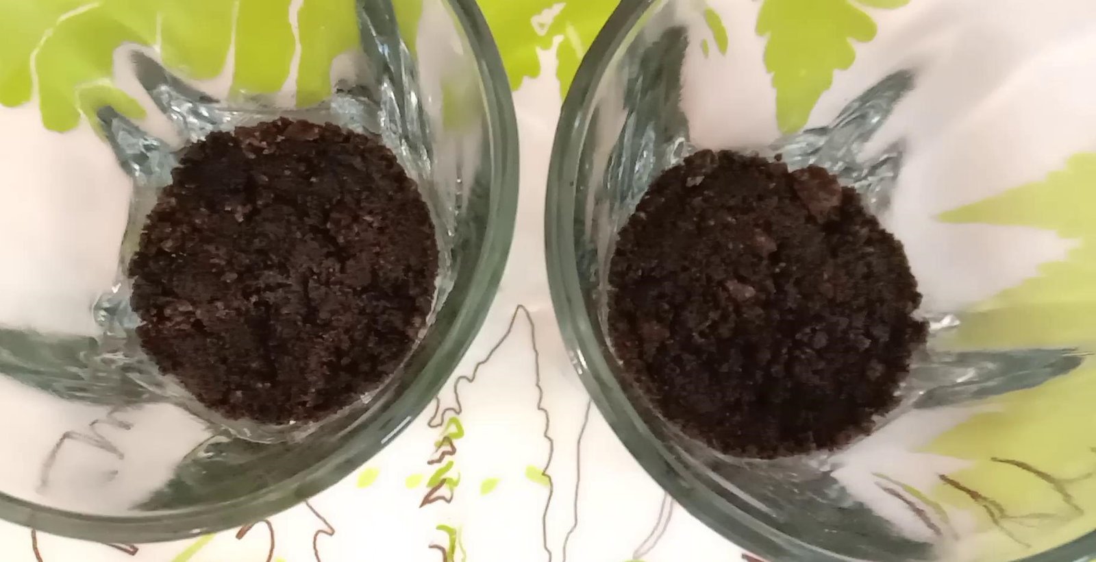 Adding powdered Oreo biscuits mixture at the bottom of both the serving glasses, Oreo pudding.